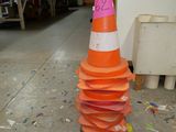 un grand cône orange sur lequel est collé un autocollant rose