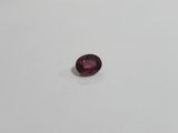 a close up of a red garnet stone on a white surface
