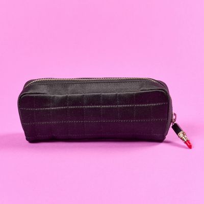 une trousse en cuir noir sur fond rose