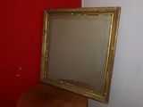 a mirror sitting on top of a stool next to a red wall