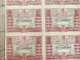 Six anciens billets de banque rouges et blancs sont exposés dans une vitrine.