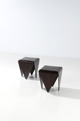 une paire de tabourets triangulaires en bois posés sur une surface blanche