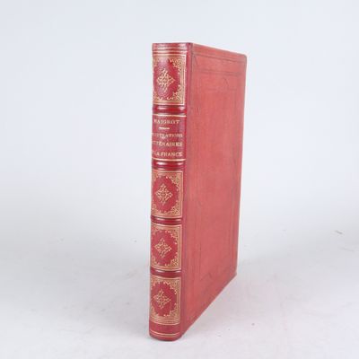 un vieux livre rouge posé sur une surface blanche