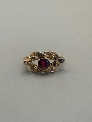 an image of a gold ring with a red stone in the middle
