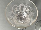 a glass with a design on it next to a glass with a wine glass in it