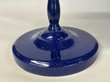 a blue glass candle holder with a candle on it