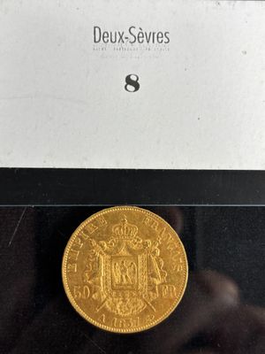 a gold coin in a glass case with a label on it