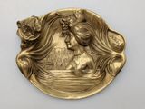 une image représentant une assiette en or sur laquelle figure une femme dans un bateau