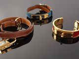 three different colored bracelets with a lock on a black surface