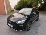 une voiture noire garée dans un parking à côté d'un bâtiment