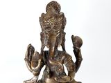 bronze statue of a seated gan on a rock holding a snake