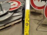 a yellow sticker on a pole in front of a pile of signs
