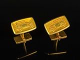 two gold cufflinks with a car on them on a black surface