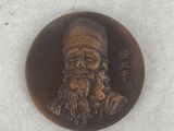 a bronze medallion of a man with a beard and a hat