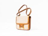 a white and tan purse with a brown strap