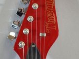 the neck of a red electric guitar with a black fretset