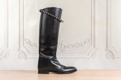 des bottes en cuir noir cloutées sur un parquet, devant un mur blanc