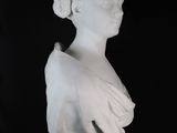 white marble bust of a woman in profile against a black background