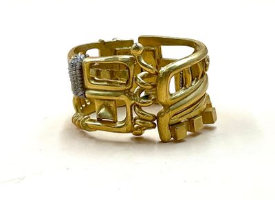 une bague en or ornée d'un train, posée sur un fond blanc
