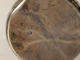 a close up of a silver pocket watch on a white surface