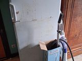 a small white refrigerator with a vacuum on the floor
