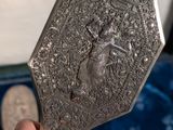someone is holding a silver mirror with a picture of a lady on it