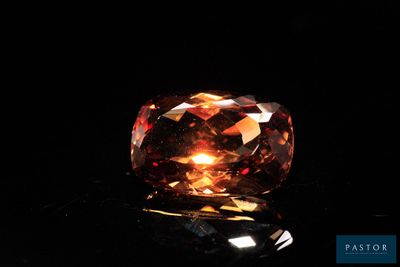 a close up view of a fancy orange diamond on a black surface