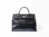a black crocodile skin handbag on a white background