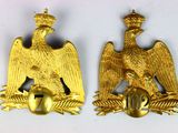 deux insignes représentant un aigle doré sur fond blanc, surmontés d'une couronne