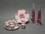 a pink and white plate and cups and saucer and a vase