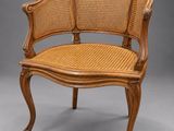 a wooden chair with wicker seat on a grey background