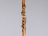 an orange and black clarinet sitting on top of a clear stand