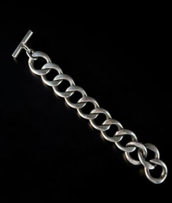 a close up of a silver bracelet on a black background