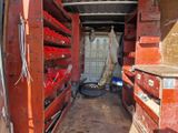 un homme debout à l'arrière d'un camion dans lequel se trouvent tout un tas d'objets