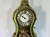 a green and gold clock sitting on a white surface
