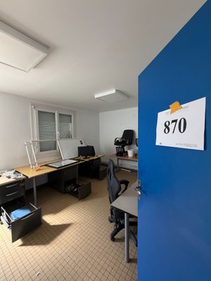 a room with a desk, chair, and a sign on the wall
