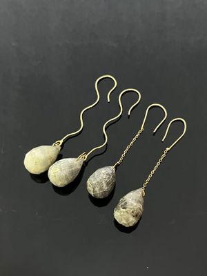 three stone drop earrings with gold chains on a black surface
