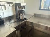 a coffee maker sitting on a stainless steel counter in a commercial kitchen