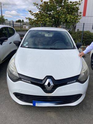 un homme debout à côté d'une voiture blanche dans un parking