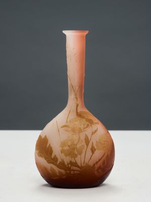 un vase orange posé sur une table blanche, près d'un mur gris