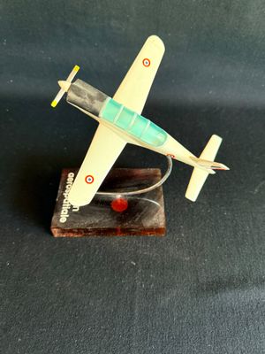 une petite maquette d'avion posée sur un socle en bois