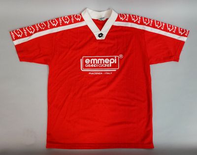 Le t-shirt est rouge et blanc, avec un motif rouge et blanc.