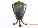 un vase bleu et vert posé sur un socle et orné d'un cordon jaune