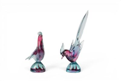 paire de figurines d'oiseaux en verre colorées posées sur un socle, sur fond blanc