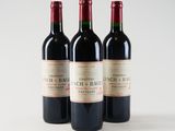 three bottles of red wine sitting on top of a white table