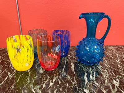 four different colored glass vases on a marble table