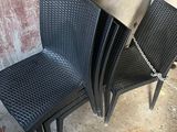 four black chairs sitting next to each other near a wall