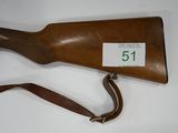 an old wooden rifle with a leather sling on a white surface