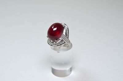 une image représentant une bague ornée d'une pierre rouge sur un support transparent