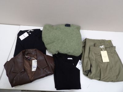 quatre paires de pantalons et un pull posés sur une table
